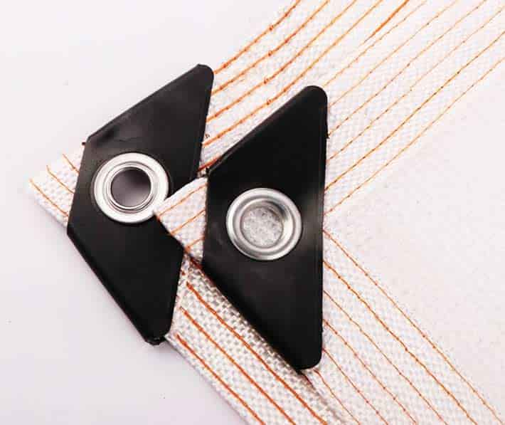 Two black triangular objects with metallic centers on a striped fabric background
